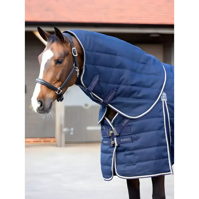 Navy blue quilted lemieux kudos stable neck cover with white trim and black leather straps for horses