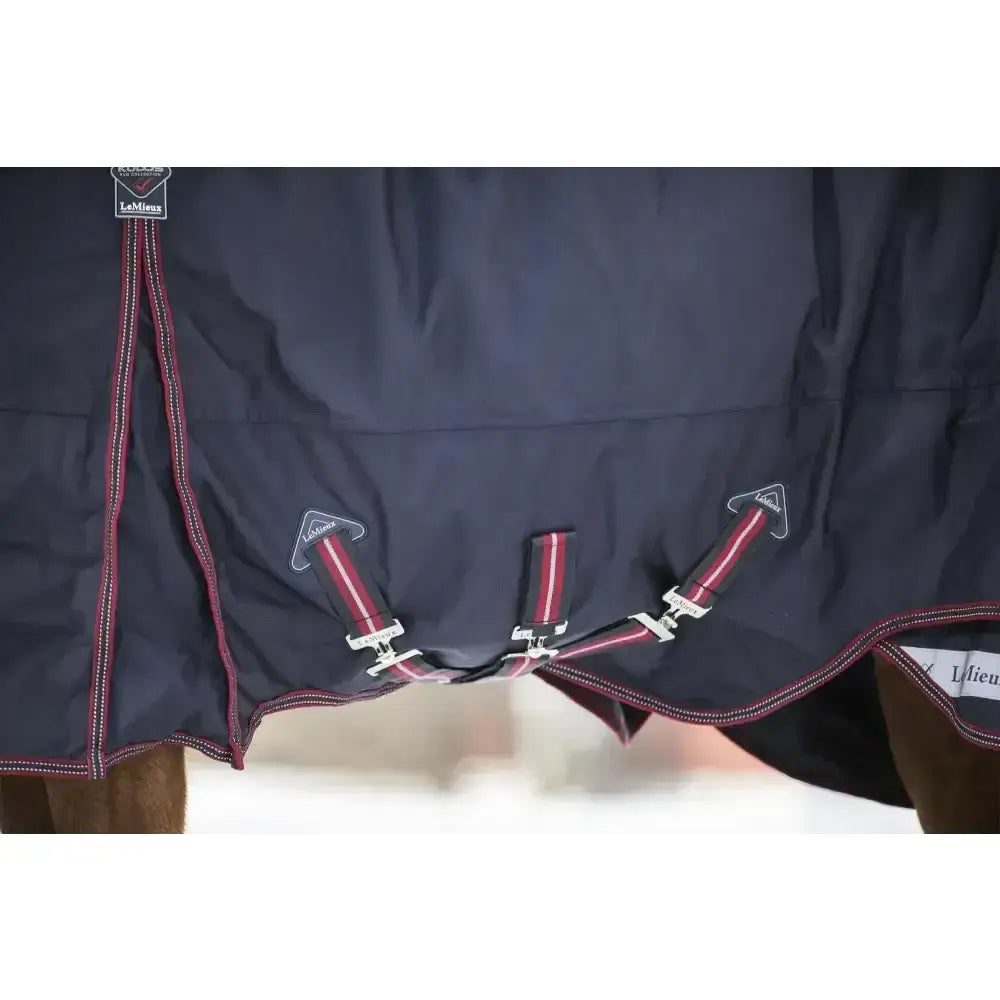 Dark navy lemieux kudos turnout rug 100g with red and white striped straps and silver buckles for horses