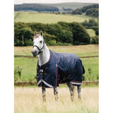 White horse in navy blue Lemieux Kudos Turnout Rug 50g standing in grassy field