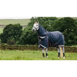 Navy blue lemieux kudos turnout rug 50g with reflective stripes and black protective leg wraps on a horse back side view