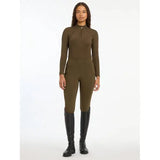 Woman in olive green jumpsuit and black knee-high boots showcasing Lemieux Ladies Base Layer Alpine