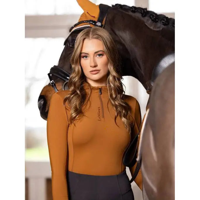 Woman in an orange Lemieux Ladies Base Layer Ginger standing beside a horse