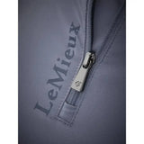 Silver zipper pull with small logo on gray fabric of lemieux ladies base layer jay blue top