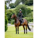 A rider in black gear on a chestnut horse with black leg wraps using lemieux loire classic close contact saddle pad black