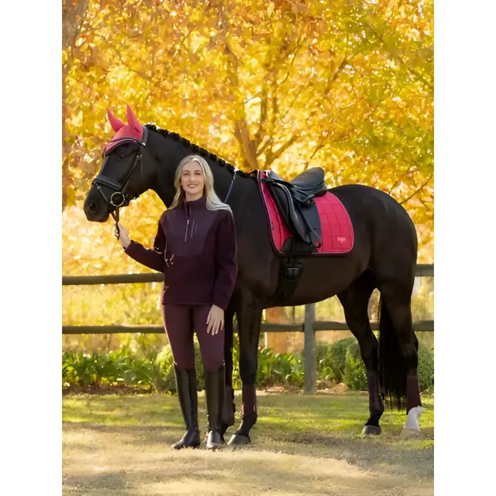 Black horse wearing a lemieux loire classic dressage square cranberry saddle pad and pink bridle side view