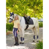 White horse wearing lemieux loire classic dressage square dusk blue with black saddle and blue leg wraps