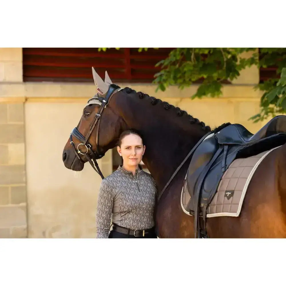 Dark brown horse wearing a lemieux loire classic dressage square walnut with blue quilted saddle pad and black bridle