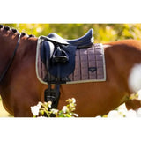 Navy blue quilted lemieux loire classic dressage square walnut saddle pad with silver trim under saddle on brown horse