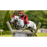 A white dapple horse jumping with a red lemiuex loire range saddle pad made of woven satin fabric