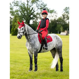 A young rider sits on a grey dapple horse wearing the red leMieux Loire range saddle pad made of woven satin fabric