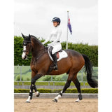 A sleek dark brown horse wearing a white lemieux loire gp square saddle pad and riding gear