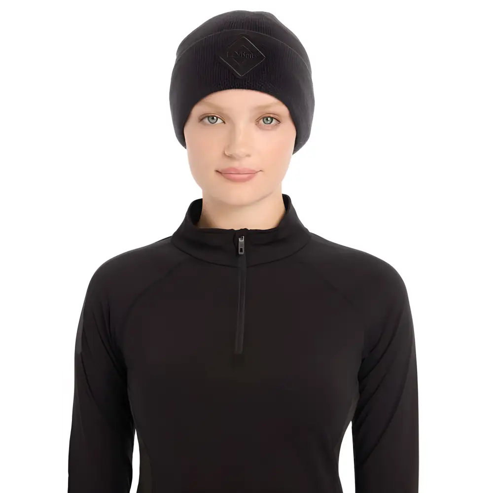 Person in a black zip-up top wearing a Lemieux Lumen Beanie Black stylishly