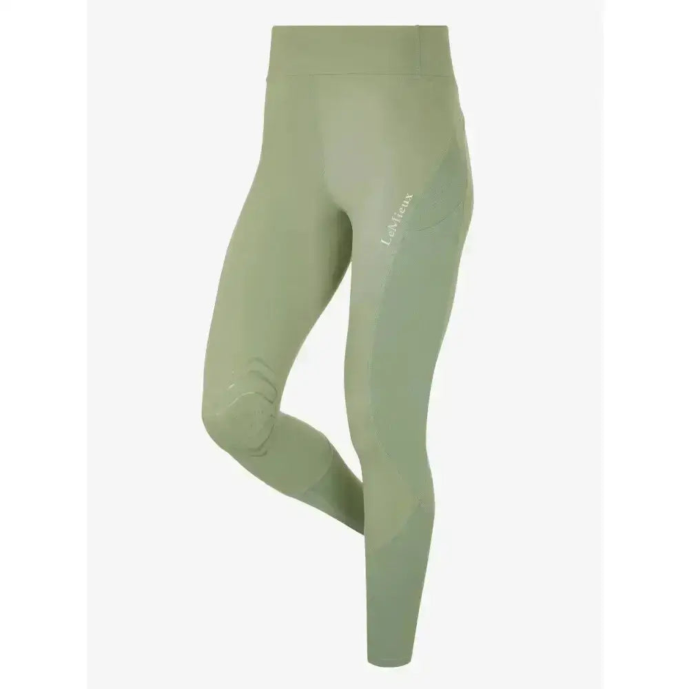 A pair of sage green lemieux lydia mesh leggings with high-waisted, sleek, form-fitting design and subtle branding on thigh