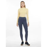 A woman wearing lemieux lydia mesh leggings dusk blue paired with a pale yellow long-sleeved high-neck top