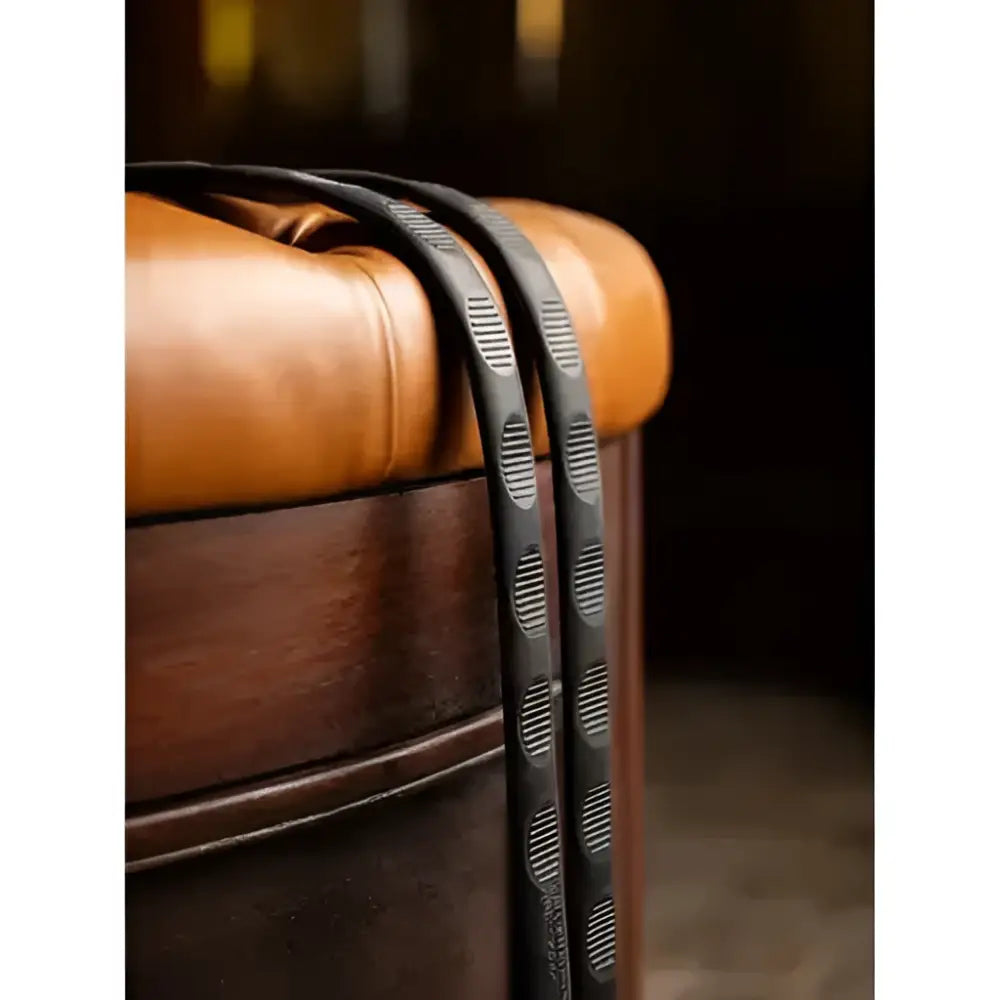 LeMieux magna grip rubber reins brown with textured oval patterned black leather strap draped over tan leather ottoman