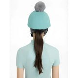 A soft teal knit beanie with a fluffy gray pom-pom from lemieux maria mesh hat silk lagoon collection