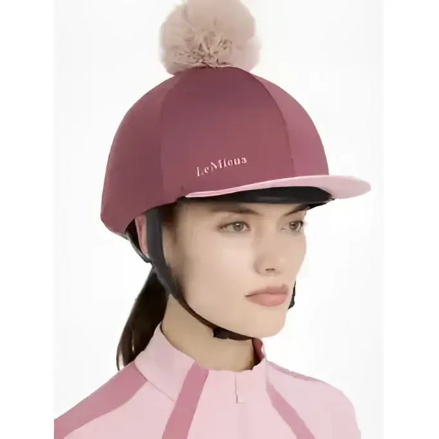 A maroon lemieux maria mesh riding helmet with a soft pink pom pom and matching pink brim silk rosewood color