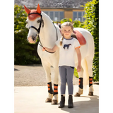 White horse with orange ears and striped leg wraps next to child in Lemieux Mini Alex Tee