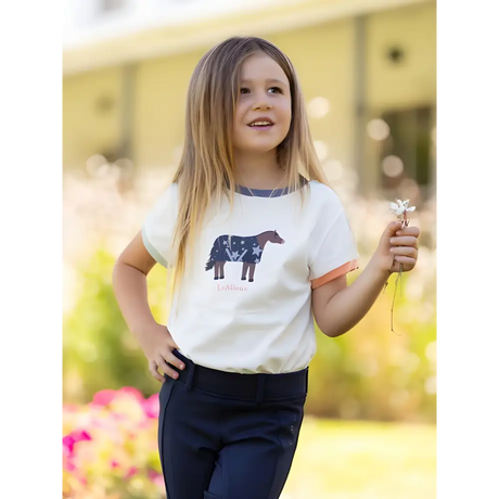 Young girl in Lemieux Mini Alex Tee Ecru with horse design and dark pants