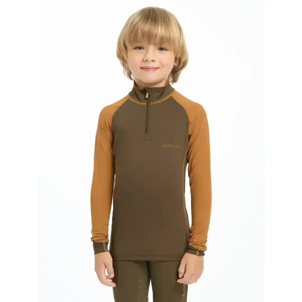 A child wearing a lemieux mini base layer alpine long sleeve brown and mustard mini riders running shirt