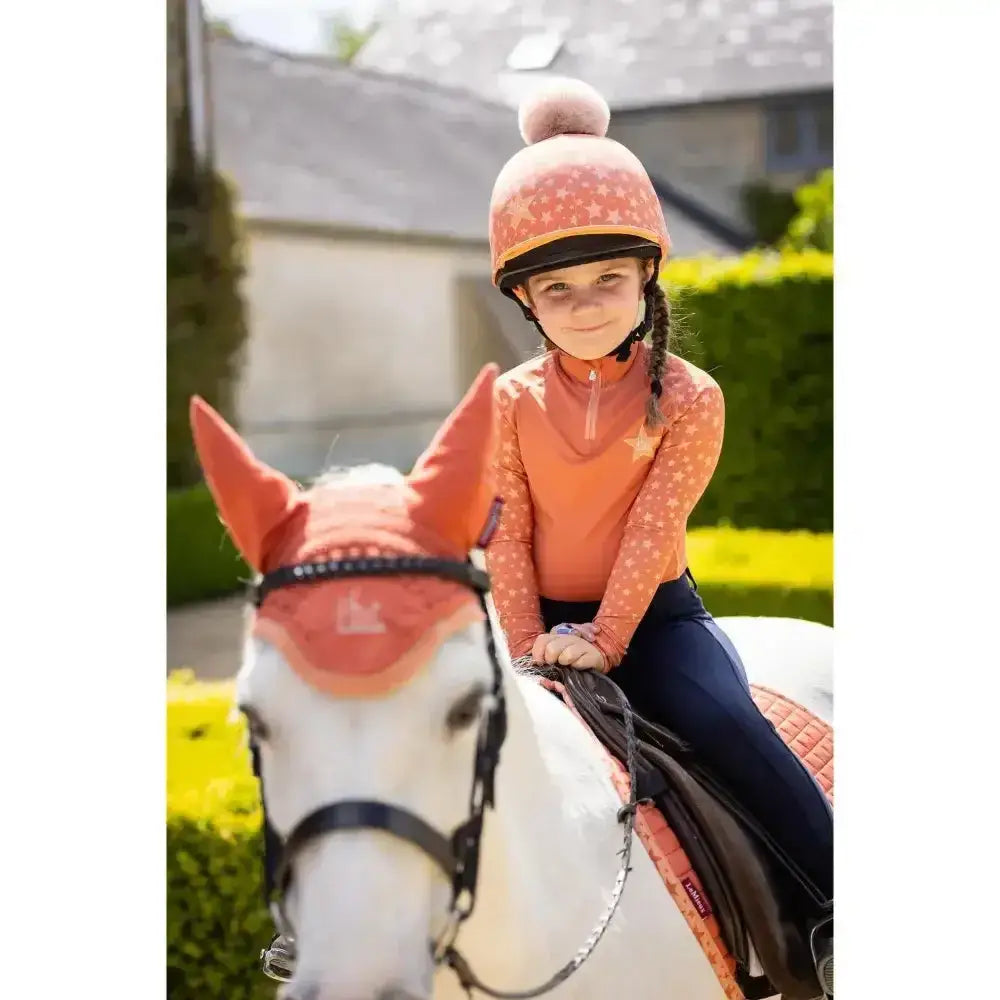 Orange patterned lemieux mini base equestrian helmet with fluffy pom pom in base layer apricot ombre star print
