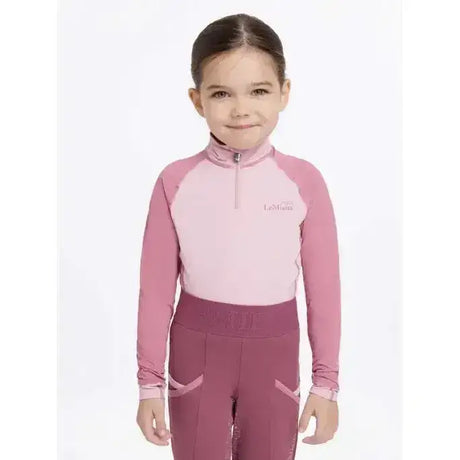 A child wearing lemieux mini base layer blossom in pink and mauve with a half-zip long sleeve top and matching leggings