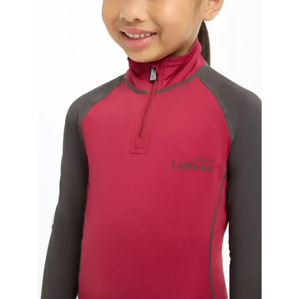 A child wearing a red and grey lemieux mini base layer ember top with half-zip and l l bean logo on chest