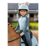 Light blue lemieux mini base equestrian helmet with fluffy pom-poms matching base layer glacier style for mini rider’s running