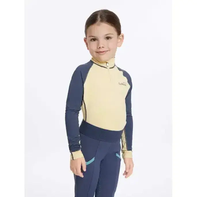 A child wearing the lemieux mini base layer mimosa in navy with teal accents, perfect for riding comfort and style