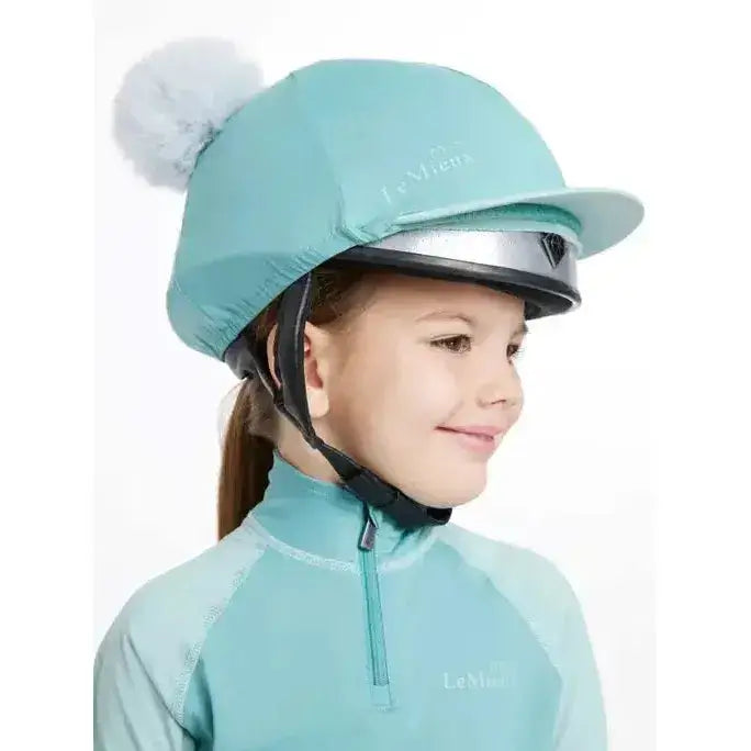 A mint green lemieux mini double pom equestrian helmet cover with a fluffy white pom-pom on top in silk lagoon
