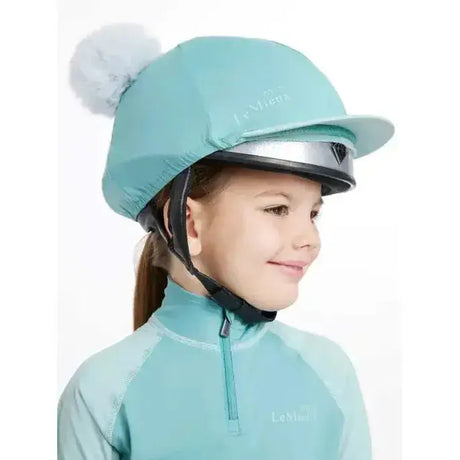 A mint green lemieux mini double pom equestrian helmet cover with a fluffy white pom-pom on top in silk lagoon
