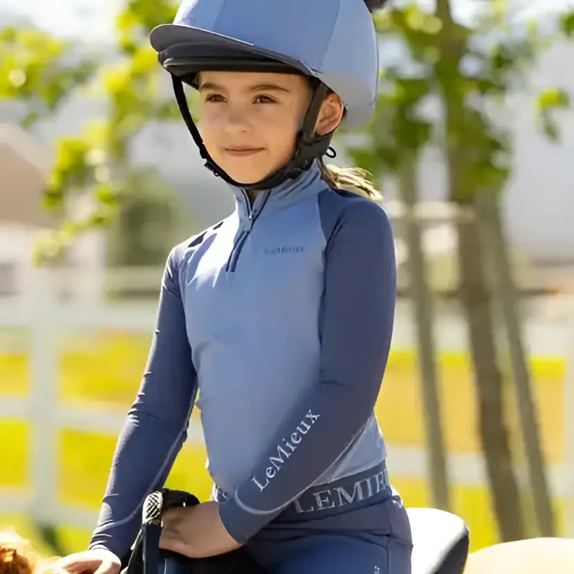 A lemieux mini double equestrian helmet in silk powder blue with a fuzzy black mini double pom on top