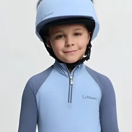 Light blue lemieux mini double equestrian helmet with silk powder blue faux fur trim and mini double pom