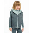 Child in teal Lemieux Mini Elsie Reversible Gilet Petrol over long-sleeved shirt