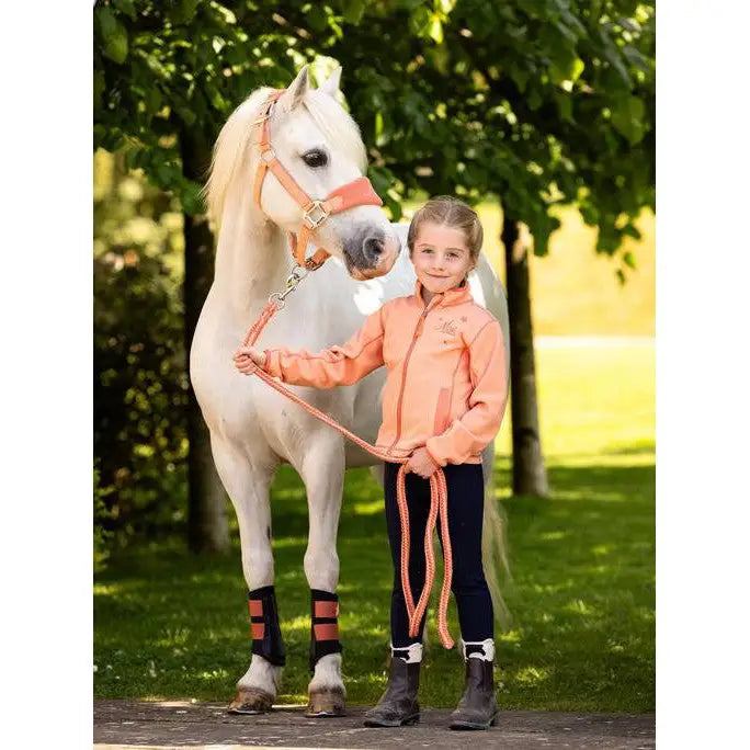 White horse beside a child wearing Lemieux Mini Grafter Boots in Apricot outdoors