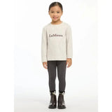 A child wearing a soft ecru lemieux mini jessie long sleeve top with black lemieux lettering across the chest