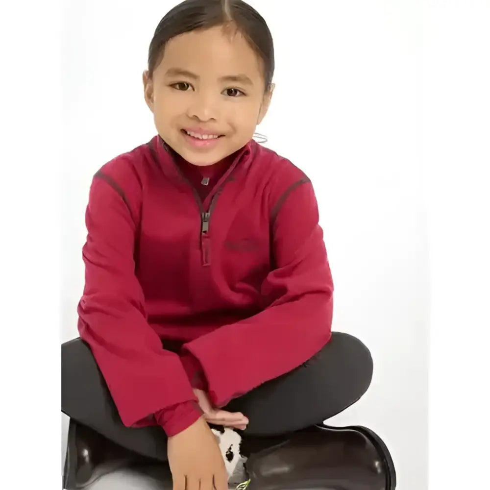 A young girl wearing lemieux mini mari micro fleece ember in maroon with gray trim zip-up fleece jacket