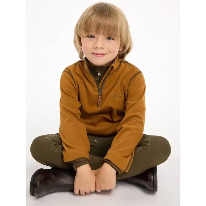 Young child in Lemieux Mini Mari Micro Fleece Ginger pullover, cross-legged