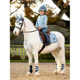 White horse with a young rider in blue featuring Lemieux Mini Mari Micro Fleece Glacier