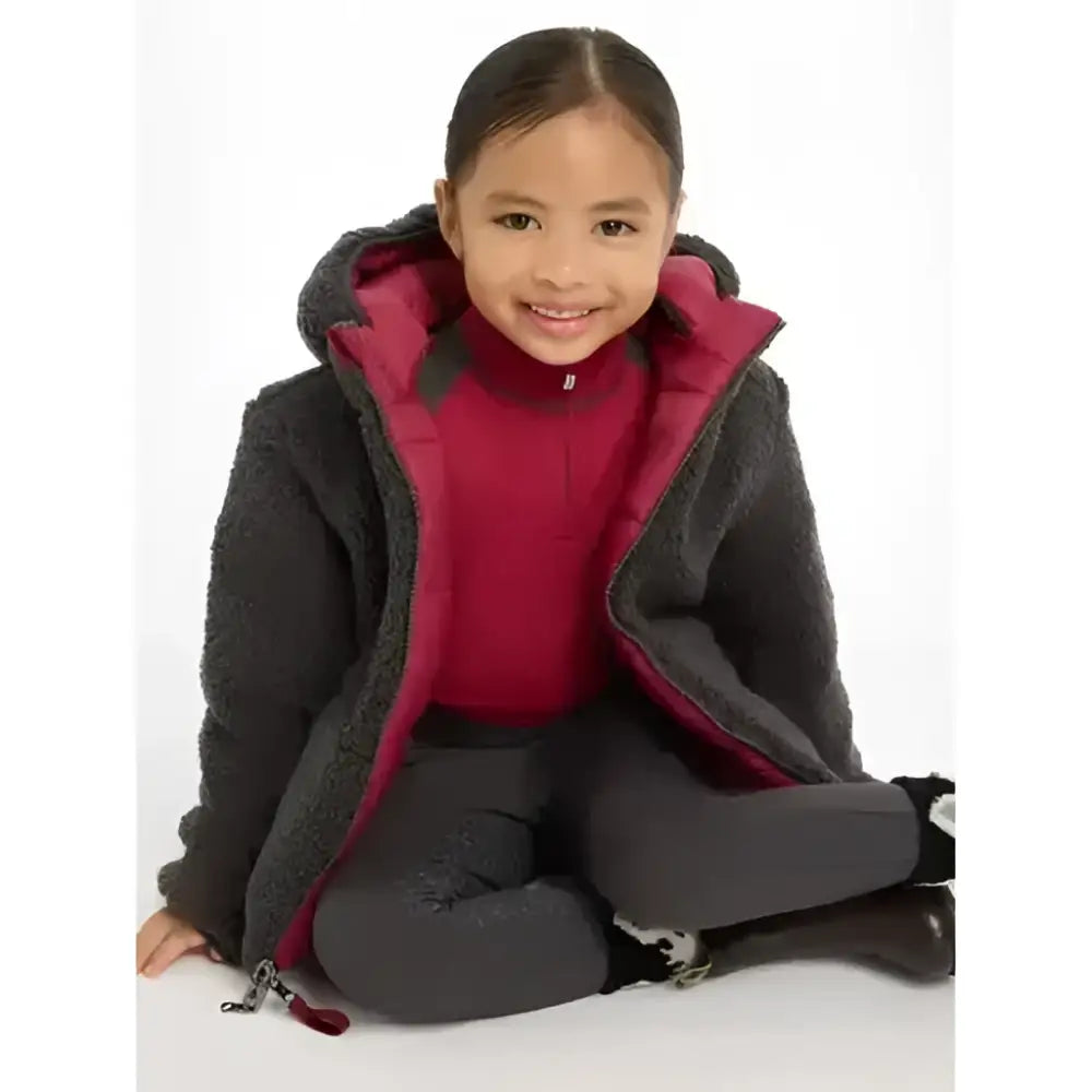 A child wearing a dark gray plush lined lemieux mini megan reversible puffer ember with vibrant magenta interior