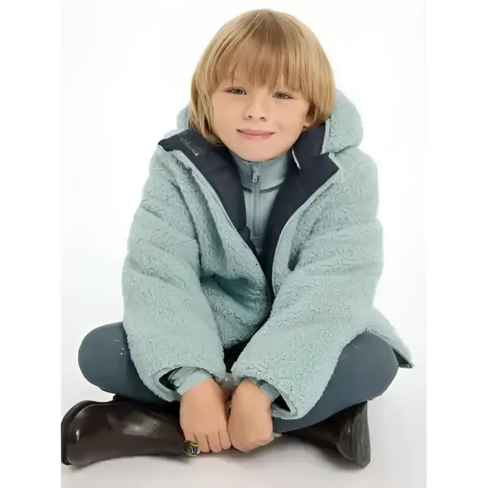 A young child wearing lemieux mini megan reversible puffer navy in light blue plush fleece with navy lining and zipper details
