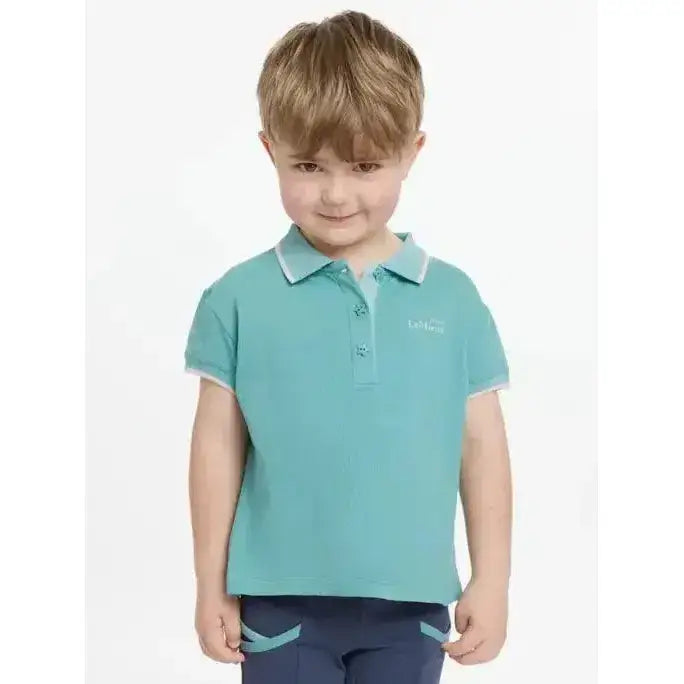 A child wearing a teal lemieux mini polo shirt lagoon with white trim and star buttons on collar and sleeve cuffs