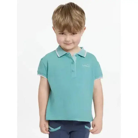 A child wearing a teal lemieux mini polo shirt lagoon with white trim and star buttons on collar and sleeve cuffs
