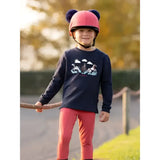 Pink helmet with black pom poms paired with lemieux mini poppy long sleeve top navy for stylish riding gear