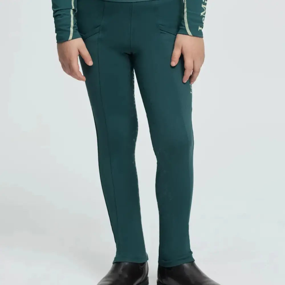 Dark green form-fitting lemieux mini pull equestrian leggings with white logo band and subtle vertical seams at the waist