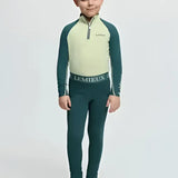 A child wearing a lemieux mini pull long-sleeved riding top with pale green torso and dark teal sleeves and leggings