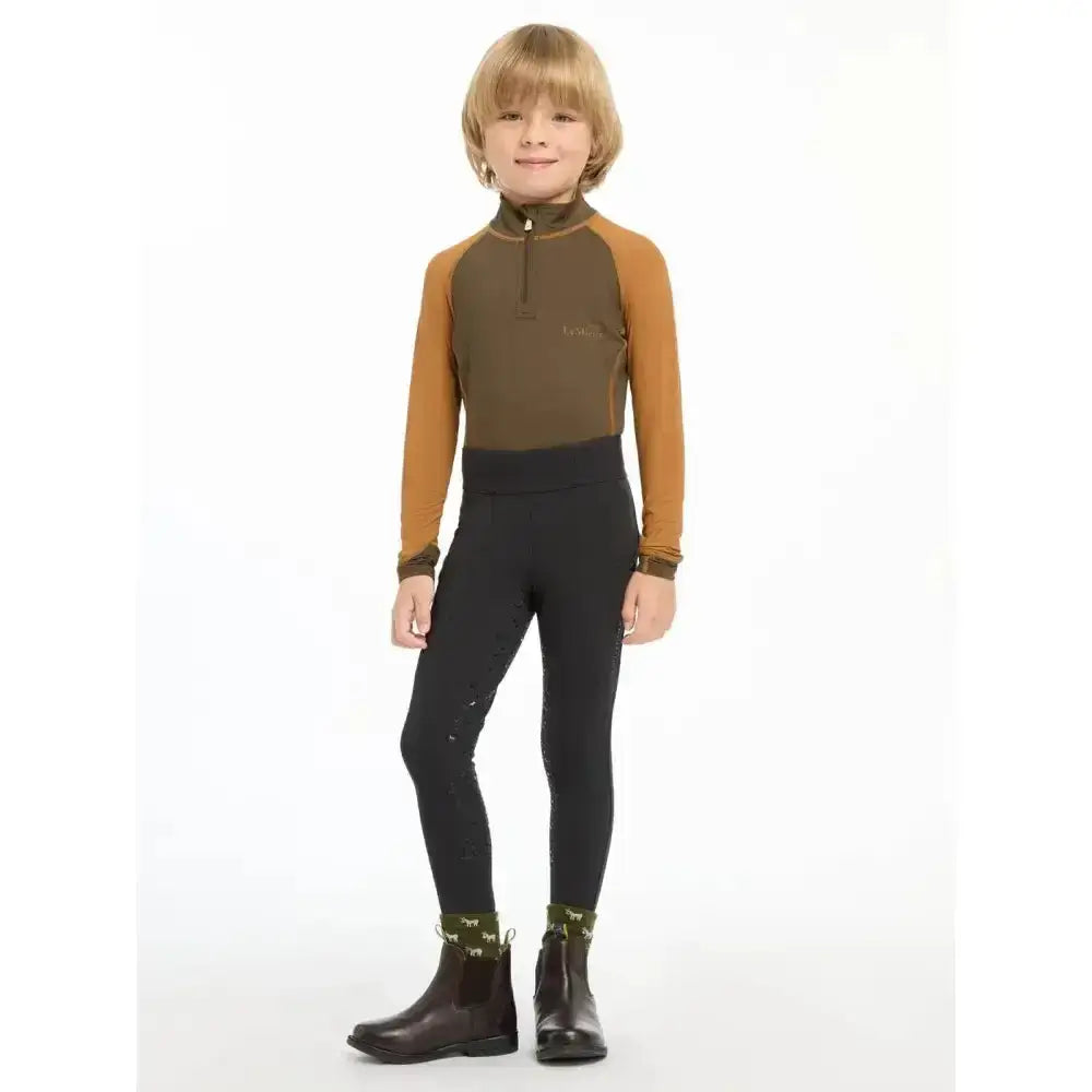 A child wearing lemieux mini pull ons black leggings paired with a two-tone olive green and tan riding top and boots