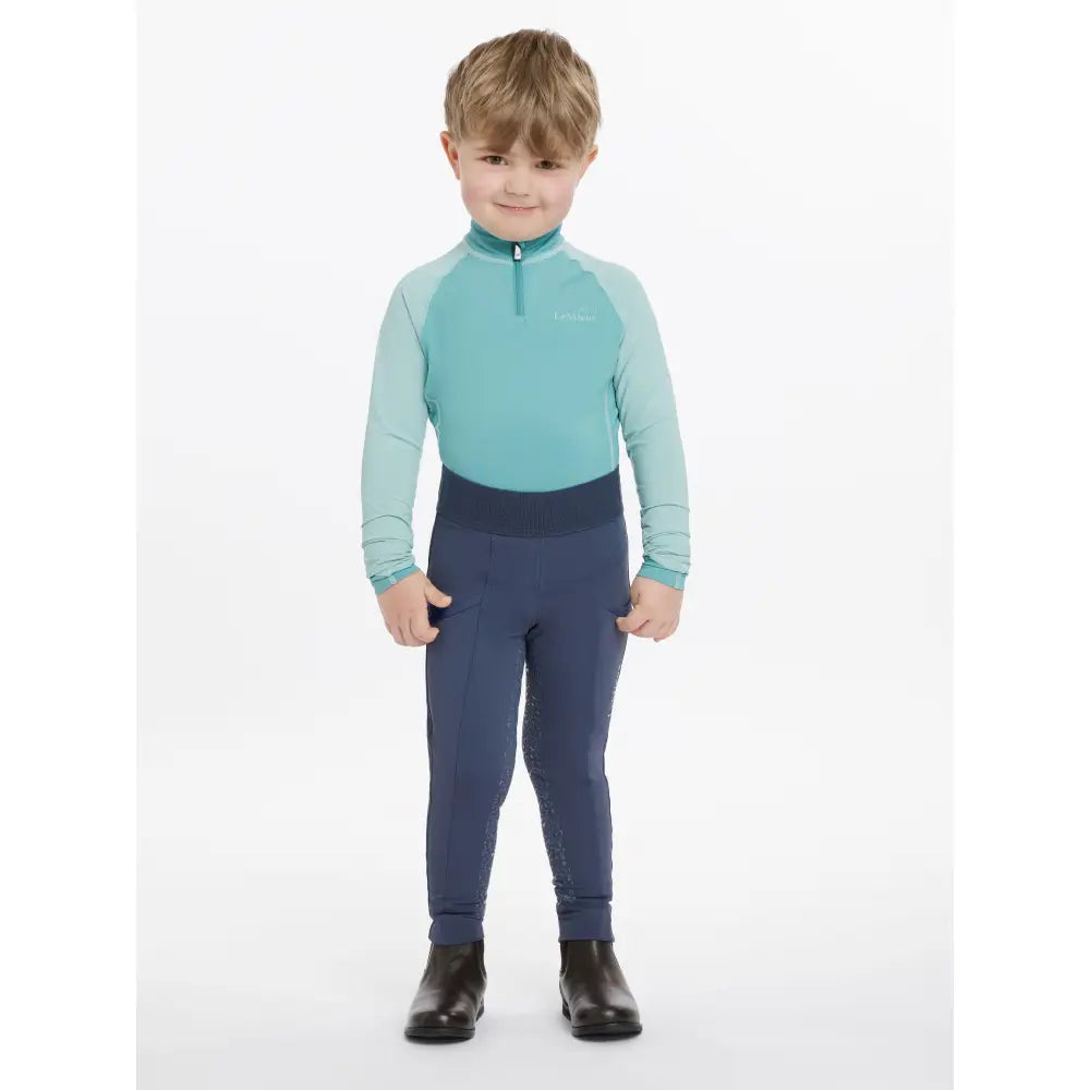 A child wearing lemieux mini pull ons dusk blue performance riding outfit with long sleeves and fitted pants