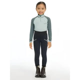 A young girl wearing lemieux mini pull navy saddle wearing mini riders with reflective stripes and dark boots