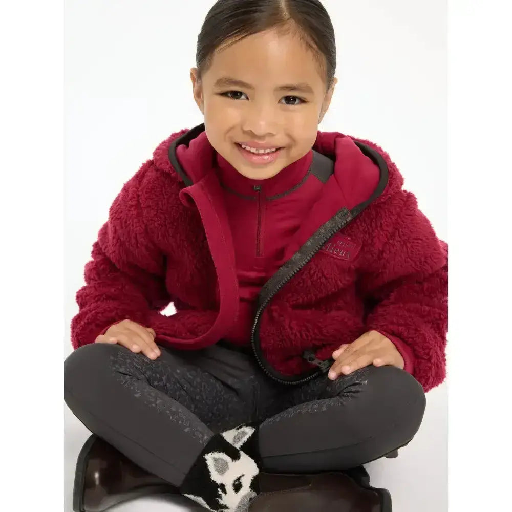 A child wearing a maroon lemieux mini teagan fleece ember jacket with black zipper and trim in plush material